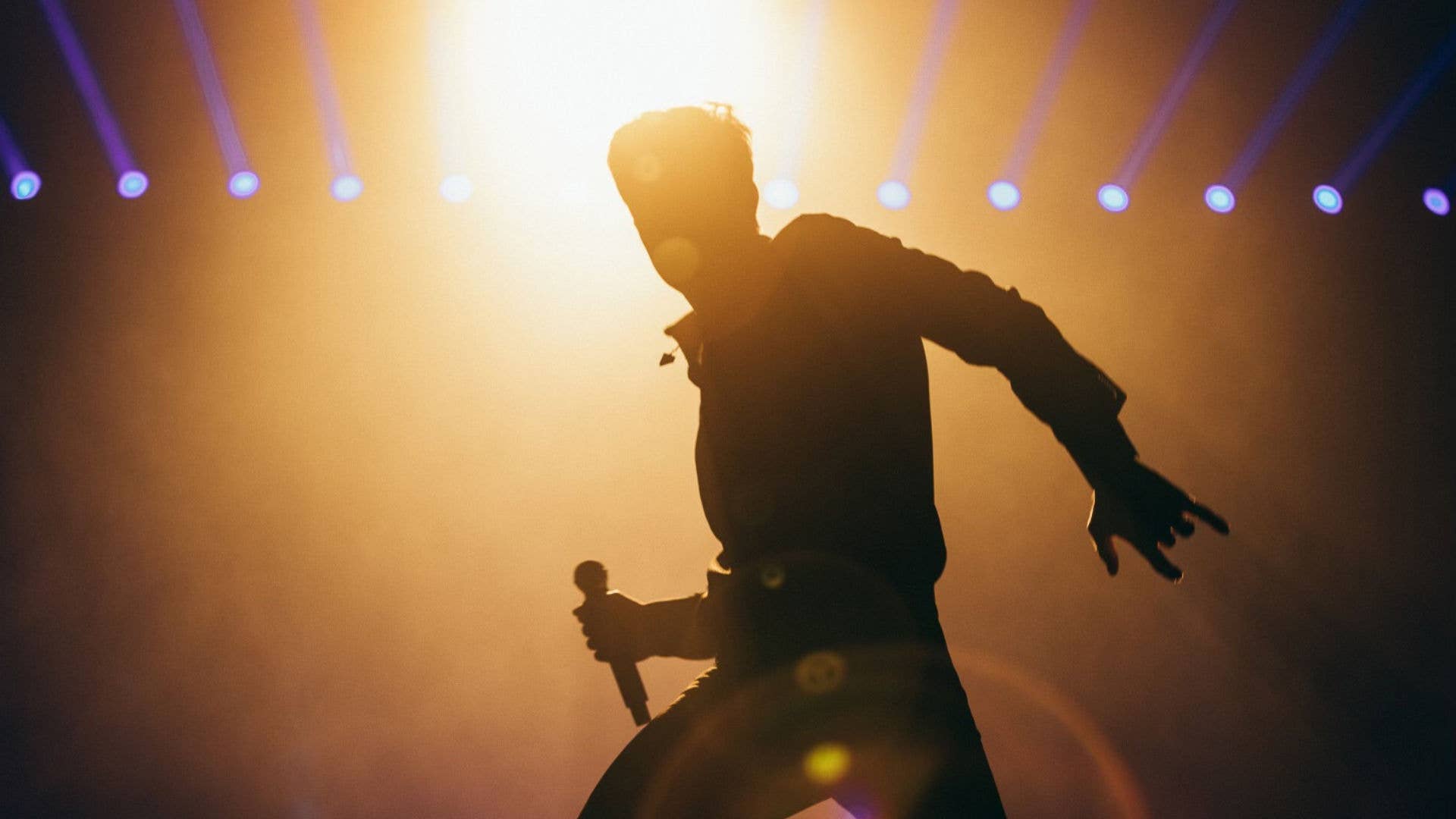 Lead singer of The Killers silhouetted by bright stage lights